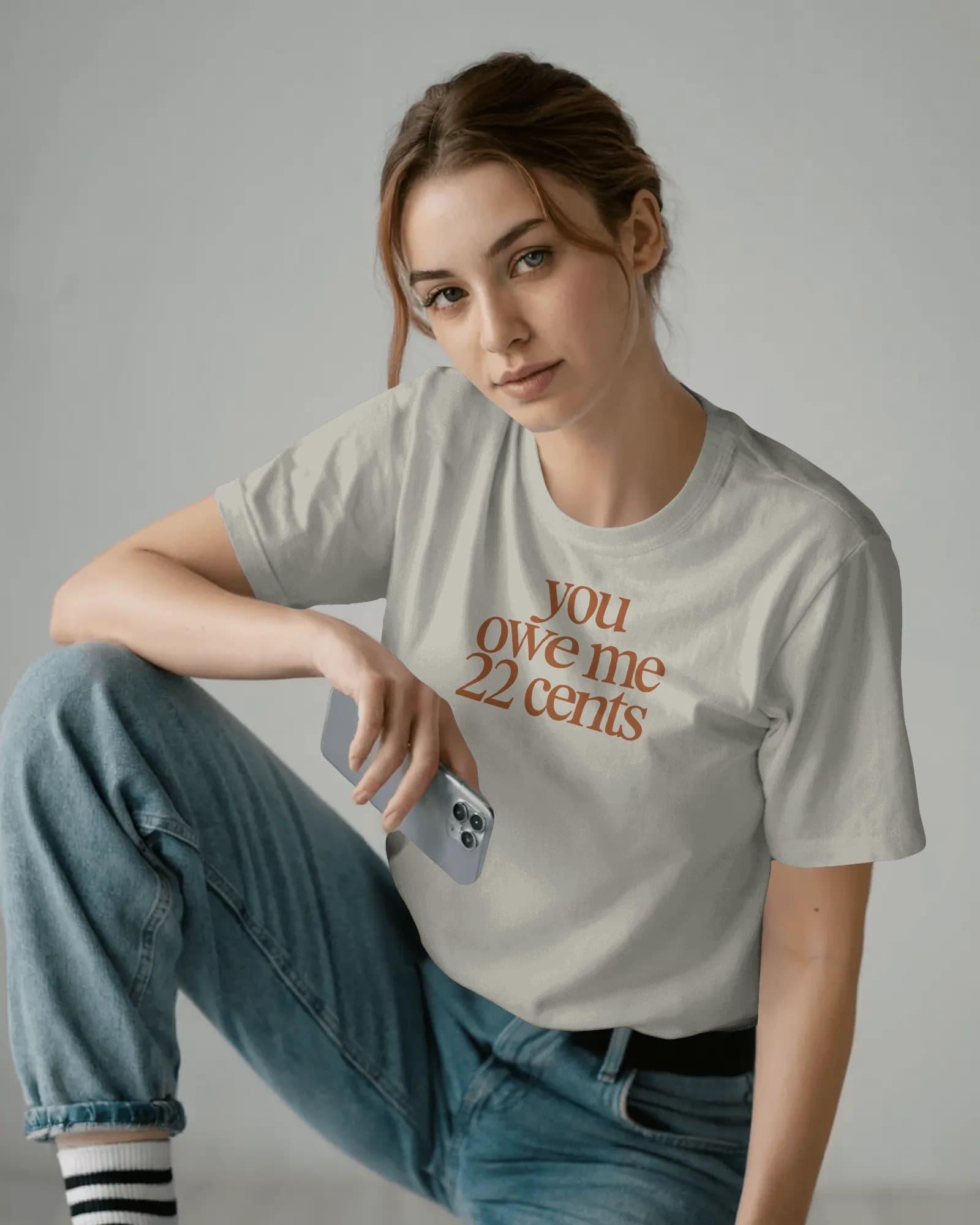 You Owe Me 22 Cents Tee — woman in cream tee with rust type, direct eye contact